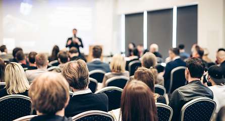 Image showing Speaker giving a talk in conference hall at business event. Rear view of unrecognizable people in audience at the conference hall. Business and entrepreneurship concept.