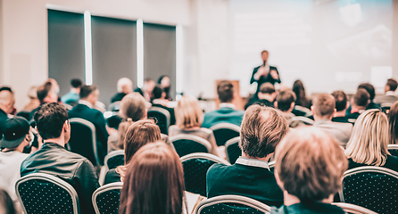 Image showing Speaker giving a talk in conference hall at business event. Rear view of unrecognizable people in audience at the conference hall. Business and entrepreneurship concept.