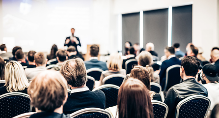 Image showing Speaker giving a talk in conference hall at business event. Rear view of unrecognizable people in audience at the conference hall. Business and entrepreneurship concept.