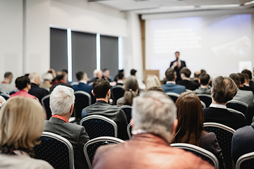 Image showing Speaker giving a talk in conference hall at business event. Rear view of unrecognizable people in audience at the conference hall. Business and entrepreneurship concept.