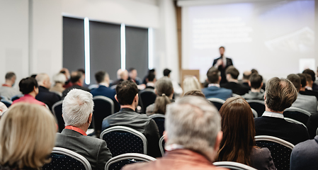 Image showing Speaker giving a talk in conference hall at business event. Rear view of unrecognizable people in audience at the conference hall. Business and entrepreneurship concept.