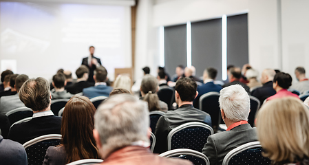 Image showing Speaker giving a talk in conference hall at business event. Rear view of unrecognizable people in audience at the conference hall. Business and entrepreneurship concept.