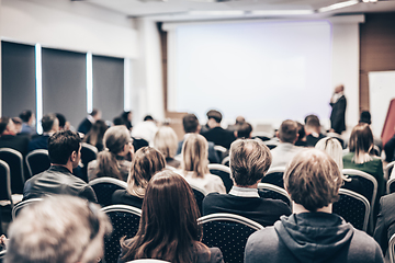 Image showing Speaker giving a talk in conference hall at business event. Rear view of unrecognizable people in audience at the conference hall. Business and entrepreneurship concept.