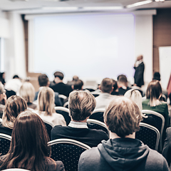 Image showing Speaker giving a talk in conference hall at business event. Rear view of unrecognizable people in audience at the conference hall. Business and entrepreneurship concept.