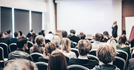 Image showing Speaker giving a talk in conference hall at business event. Rear view of unrecognizable people in audience at the conference hall. Business and entrepreneurship concept.