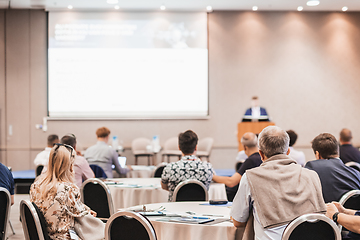 Image showing Speaker giving a talk in conference hall at business event. Rear view of unrecognizable people in audience at the conference hall. Business and entrepreneurship concept.