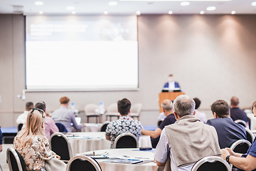 Image showing Speaker giving a talk in conference hall at business event. Rear view of unrecognizable people in audience at the conference hall. Business and entrepreneurship concept.