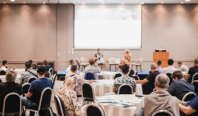 Image showing Speaker giving a talk in conference hall at business event. Rear view of unrecognizable people in audience at the conference hall. Business and entrepreneurship concept.