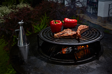 Image showing Tomahawk rib beef steak and T-bone on hot black grill.