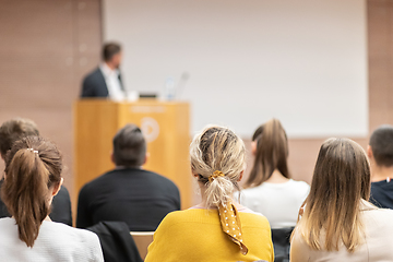 Image showing Speaker giving a talk in conference hall at business event. Rear view of unrecognizable people in audience at the conference hall. Business and entrepreneurship concept.