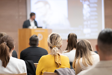 Image showing Speaker giving a talk in conference hall at business event. Rear view of unrecognizable people in audience at the conference hall. Business and entrepreneurship concept.