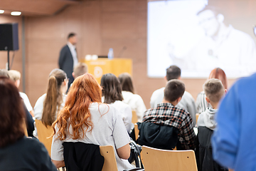 Image showing Speaker giving a talk in conference hall at business event. Rear view of unrecognizable people in audience at the conference hall. Business and entrepreneurship concept.