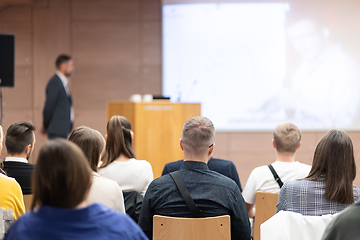 Image showing Speaker giving a talk in conference hall at business event. Rear view of unrecognizable people in audience at the conference hall. Business and entrepreneurship concept.