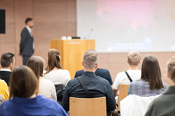 Image showing Speaker giving a talk in conference hall at business event. Rear view of unrecognizable people in audience at the conference hall. Business and entrepreneurship concept.