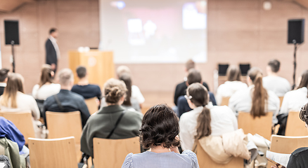 Image showing Speaker giving a talk in conference hall at business event. Rear view of unrecognizable people in audience at the conference hall. Business and entrepreneurship concept.