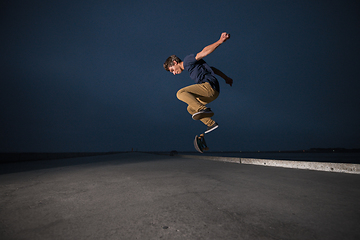 Image showing Skateboarder performing a ollie flip on a concrete pavement