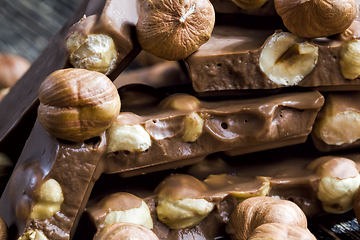 Image showing bitter real chocolate, photographed close-up with whole hazelnuts inside and next to a bar of broken chocolate