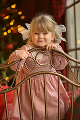 Image showing Little cute blond girl standing at headboard of iron bed