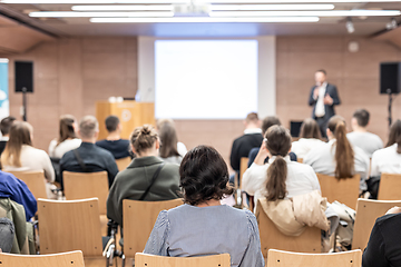 Image showing Speaker giving a talk in conference hall at business event. Rear view of unrecognizable people in audience at the conference hall. Business and entrepreneurship concept.