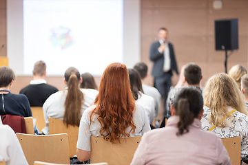 Image showing Speaker giving a talk in conference hall at business event. Rear view of unrecognizable people in audience at the conference hall. Business and entrepreneurship concept.