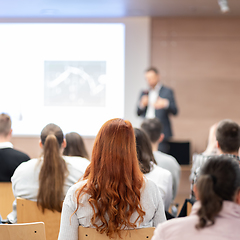 Image showing Speaker giving a talk in conference hall at business event. Rear view of unrecognizable people in audience at the conference hall. Business and entrepreneurship concept.