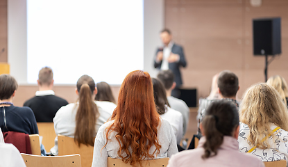 Image showing Speaker giving a talk in conference hall at business event. Rear view of unrecognizable people in audience at the conference hall. Business and entrepreneurship concept.