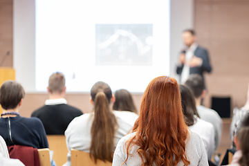 Image showing Speaker giving a talk in conference hall at business event. Rear view of unrecognizable people in audience at the conference hall. Business and entrepreneurship concept.