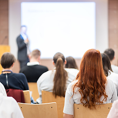 Image showing Speaker giving a talk in conference hall at business event. Rear view of unrecognizable people in audience at the conference hall. Business and entrepreneurship concept.