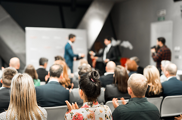 Image showing Business team leader receiving award prize at best business project competition event. Business and entrepreneurship award ceremony theme. Focus on unrecognizable people in audience.