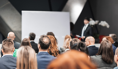 Image showing Speaker giving a talk in conference hall at business event. Rear view of unrecognizable people in audience at the conference hall. Business and entrepreneurship concept.