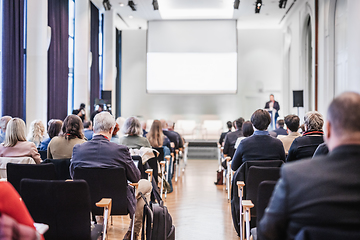 Image showing Speaker giving a talk in conference hall at business event. Rear view of unrecognizable people in audience at the conference hall. Business and entrepreneurship concept.