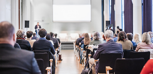 Image showing Speaker giving a talk in conference hall at business event. Rear view of unrecognizable people in audience at the conference hall. Business and entrepreneurship concept.