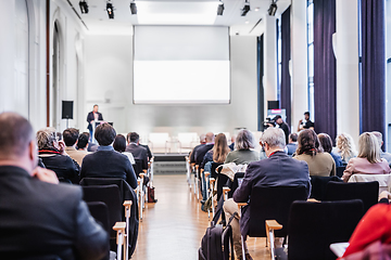 Image showing Speaker giving a talk in conference hall at business event. Rear view of unrecognizable people in audience at the conference hall. Business and entrepreneurship concept.