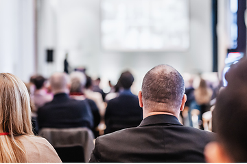 Image showing Speaker giving a talk in conference hall at business event. Rear view of unrecognizable people in audience at the conference hall. Business and entrepreneurship concept.