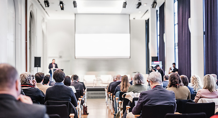 Image showing Speaker giving a talk in conference hall at business event. Rear view of unrecognizable people in audience at the conference hall. Business and entrepreneurship concept.