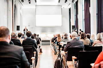 Image showing Speaker giving a talk in conference hall at business event. Rear view of unrecognizable people in audience at the conference hall. Business and entrepreneurship concept.