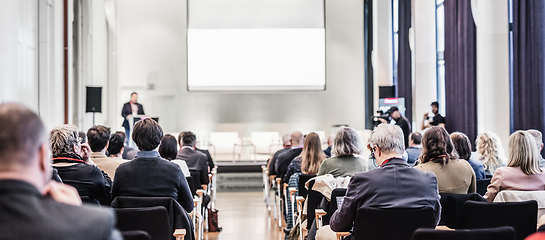 Image showing Speaker giving a talk in conference hall at business event. Rear view of unrecognizable people in audience at the conference hall. Business and entrepreneurship concept.