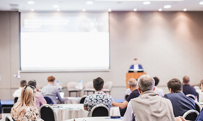 Image showing Speaker giving a talk in conference hall at business event. Rear view of unrecognizable people in audience at the conference hall. Business and entrepreneurship concept.