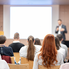 Image showing Speaker giving a talk in conference hall at business event. Rear view of unrecognizable people in audience at the conference hall. Business and entrepreneurship concept.