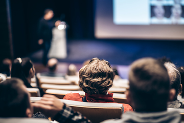 Image showing Speaker giving a talk in conference hall at business event. Rear view of unrecognizable people in audience at the conference hall. Business and entrepreneurship concept.