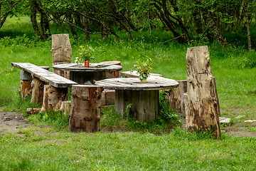 Image showing picnic area made of old wood in the forest decorated with flower