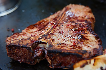 Image showing Grilled T-Bone Steak on serving board on wooden background