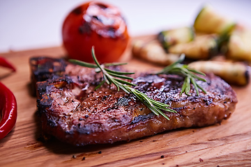 Image showing Grilled T-Bone Steak on serving board on wooden background