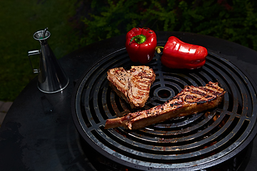 Image showing Tomahawk rib beef steak and T-bone on hot black grill.