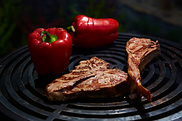 Image showing Tomahawk rib beef steak and T-bone on hot black grill.