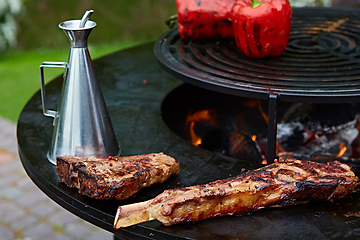 Image showing Tomahawk rib beef steak and T-bone on hot black grill.