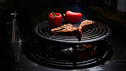 Image showing Tomahawk rib beef steak and T-bone on hot black grill.