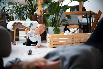 Image showing Happy family moments. Mother lying comfortably on children's mat watching and suppervising her baby boy playinghis in living room. Positive human emotions, feelings, joy