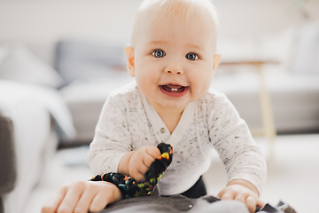 Image showing Cute infant baby boy playing, crawling and standing upat home. Baby playing at home