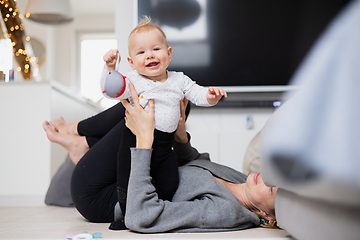 Image showing Happy family moments. Mother lying comfortably on children's mat playing with her baby boy watching and suppervising his first steps. Positive human emotions, feelings, joy.